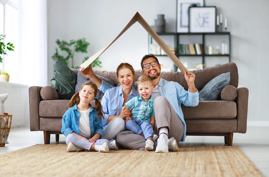 Family Sitting in Living Room With Cardboard Box Roof Over Their Head